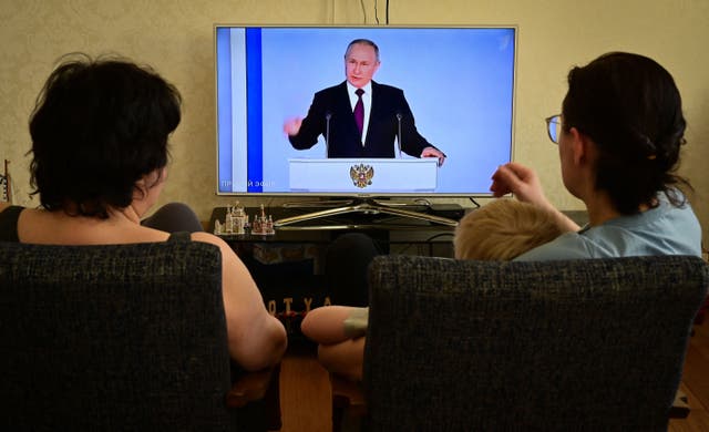<p>A family watching Putin’s speech on television at home in Moscow</p>