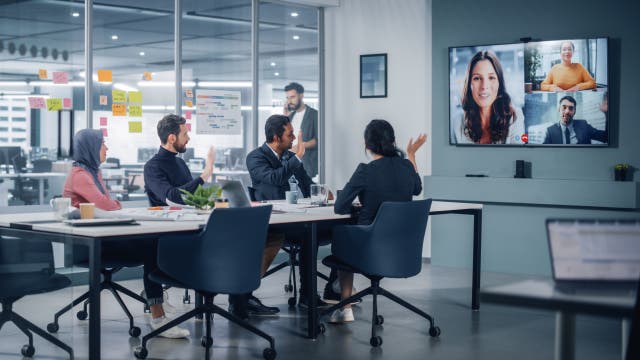 <p>Businesspeople do Video Conference Call with Big Wall TV in Office Meeting Room. Diverse Team of Creative Entrepreneurs at Big Table have Discussion. Specialists work in Digital e-Commerce Startup</p>