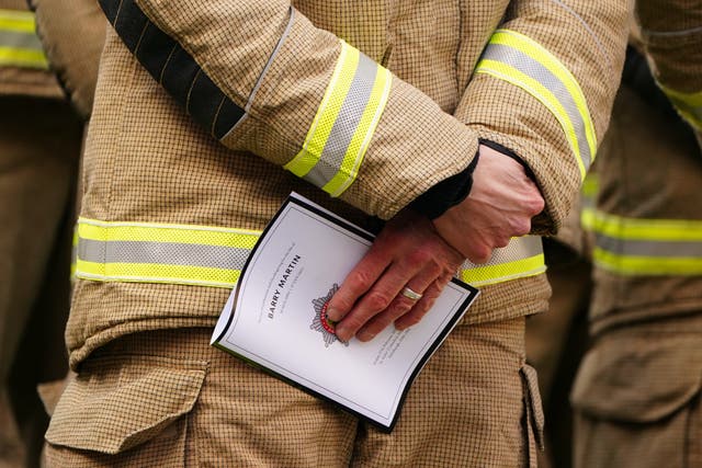 A firefighter holding a copy of the Order of Service for the funeral of Barry Martin (Jane Barlow/PA)