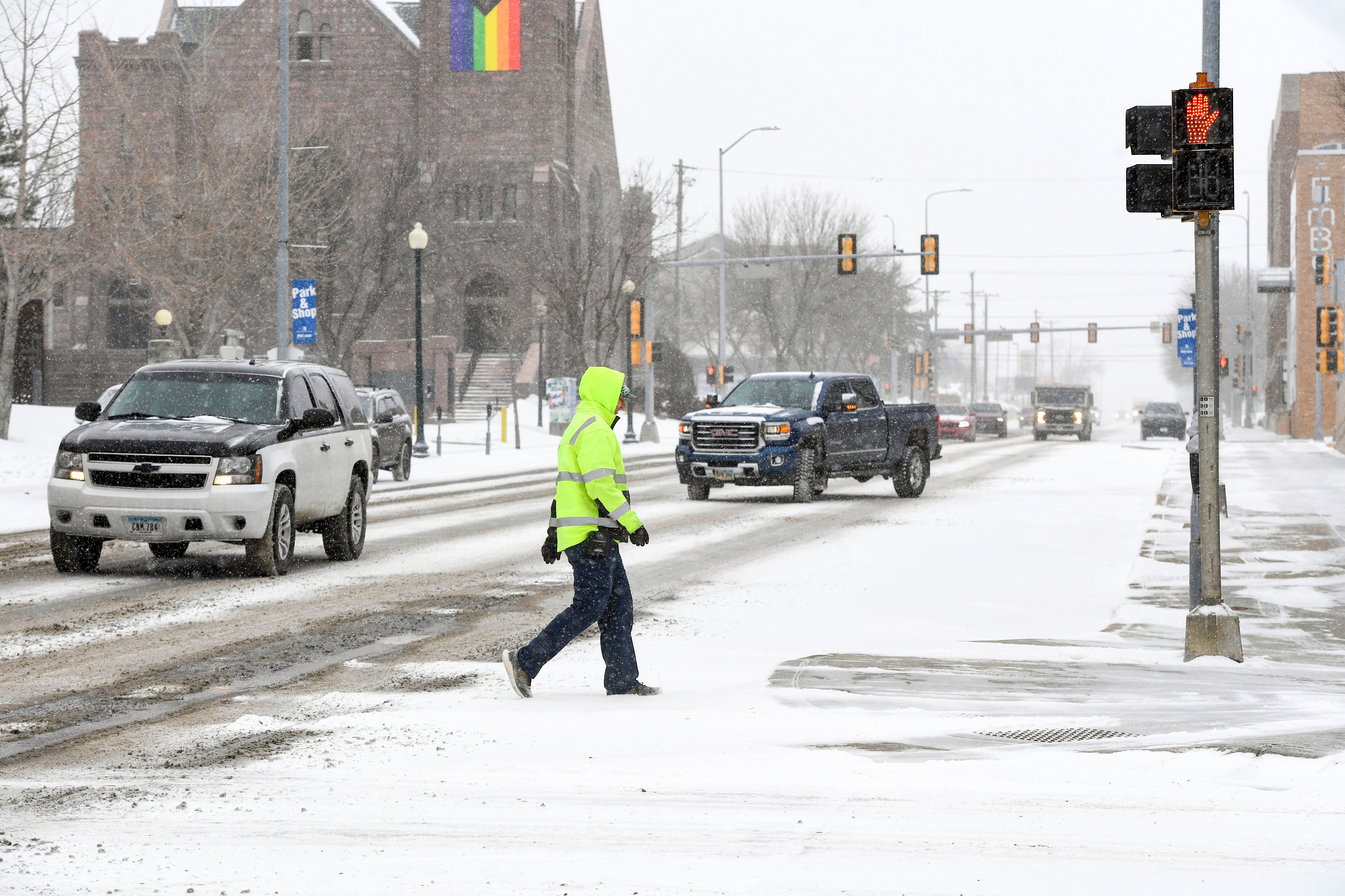A pedestrian walks across town as the first snow falls ahead of a winter storm on Tuesday in Sioux Falls, South Dakota