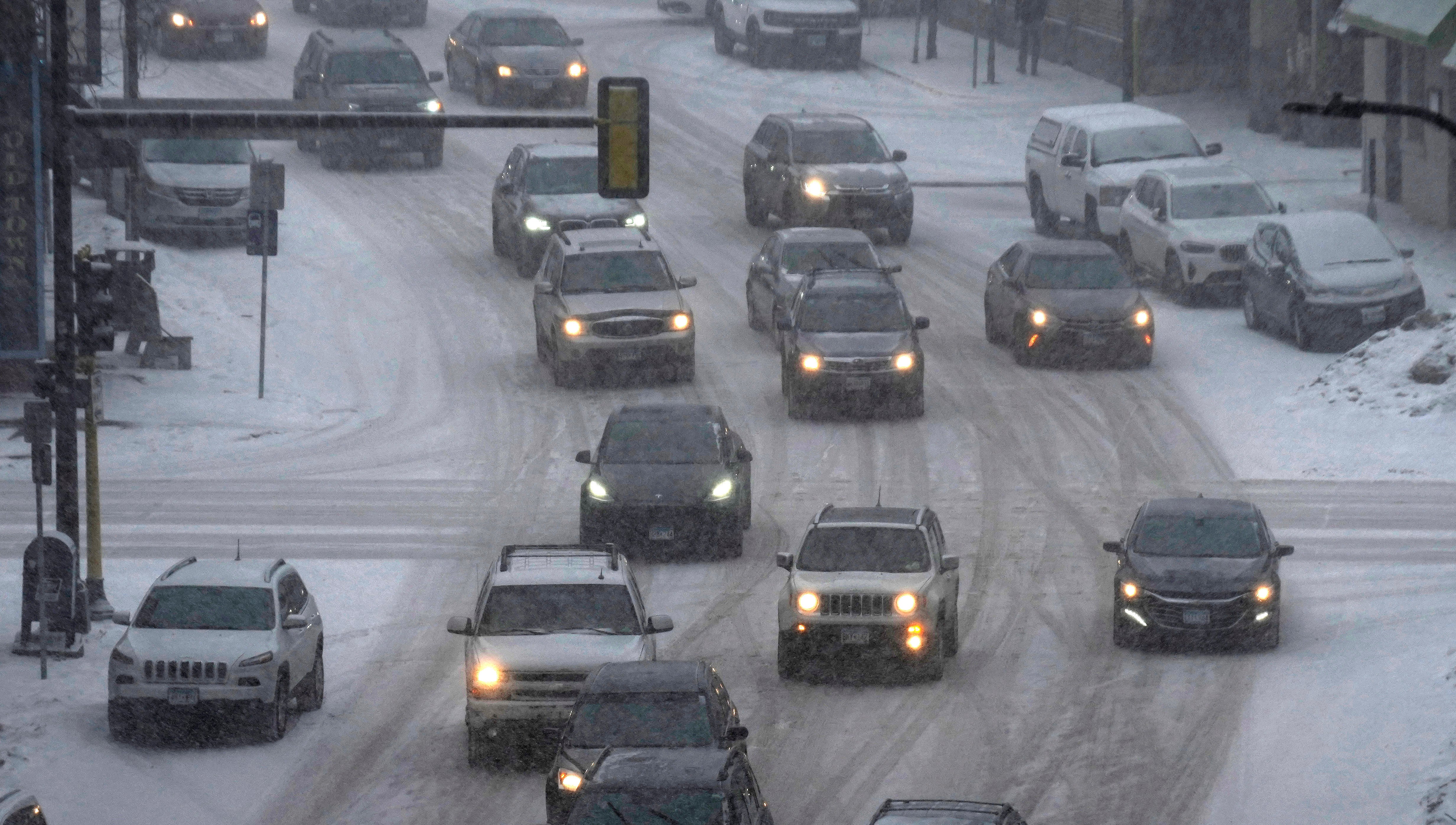 Vehicles drive in downtown Minneapolis as snow falls on Tuesday