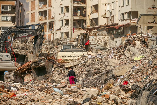 <p>A man walks among debris as excavators demolish the remains of a destroyed building following the earthquake in Samandag, southern Turkey </p>