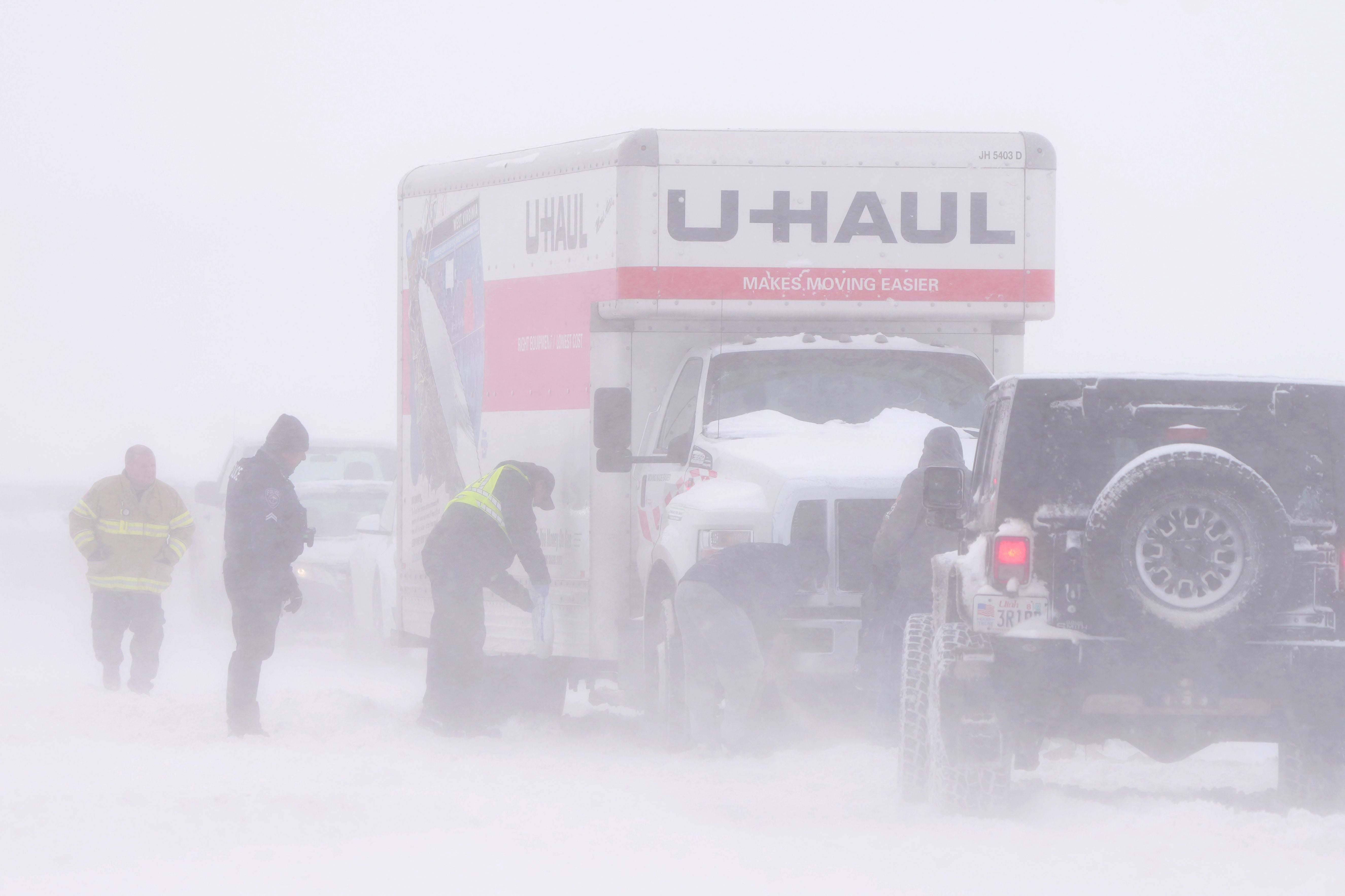 Police and emergency workers try to free a U-Hall moving truck from the snow on Mountain View Parkway in Lehi, Utah, on February 22, 2023