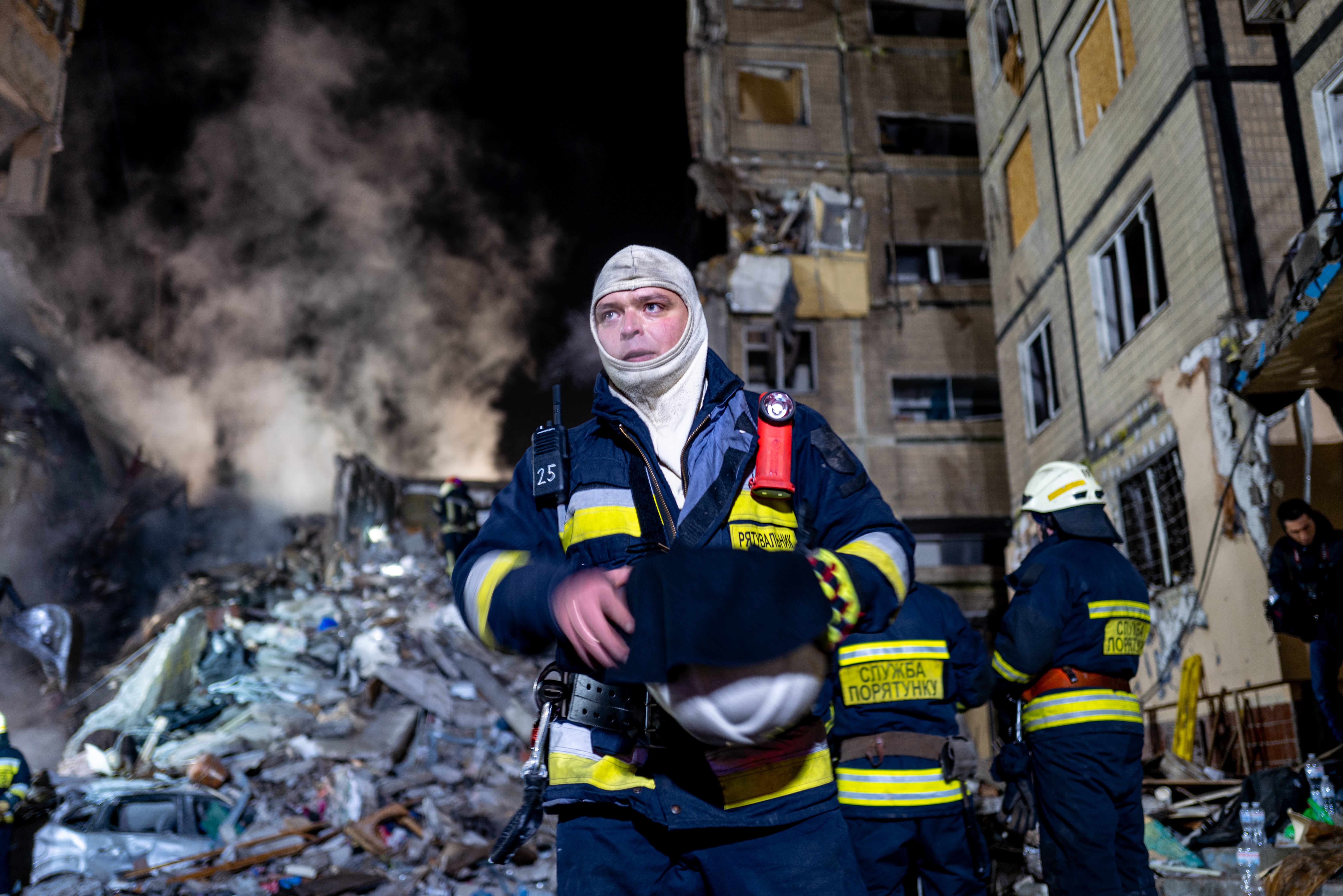 Emergency workers search the remains of the building struck in Dnipro