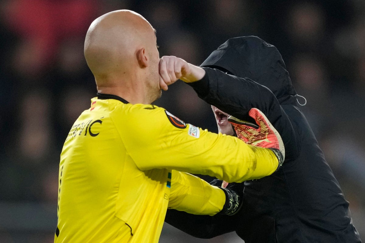 Sevilla goalkeeper Marko Dmitrovic attacked by pitch invader in PSV clash