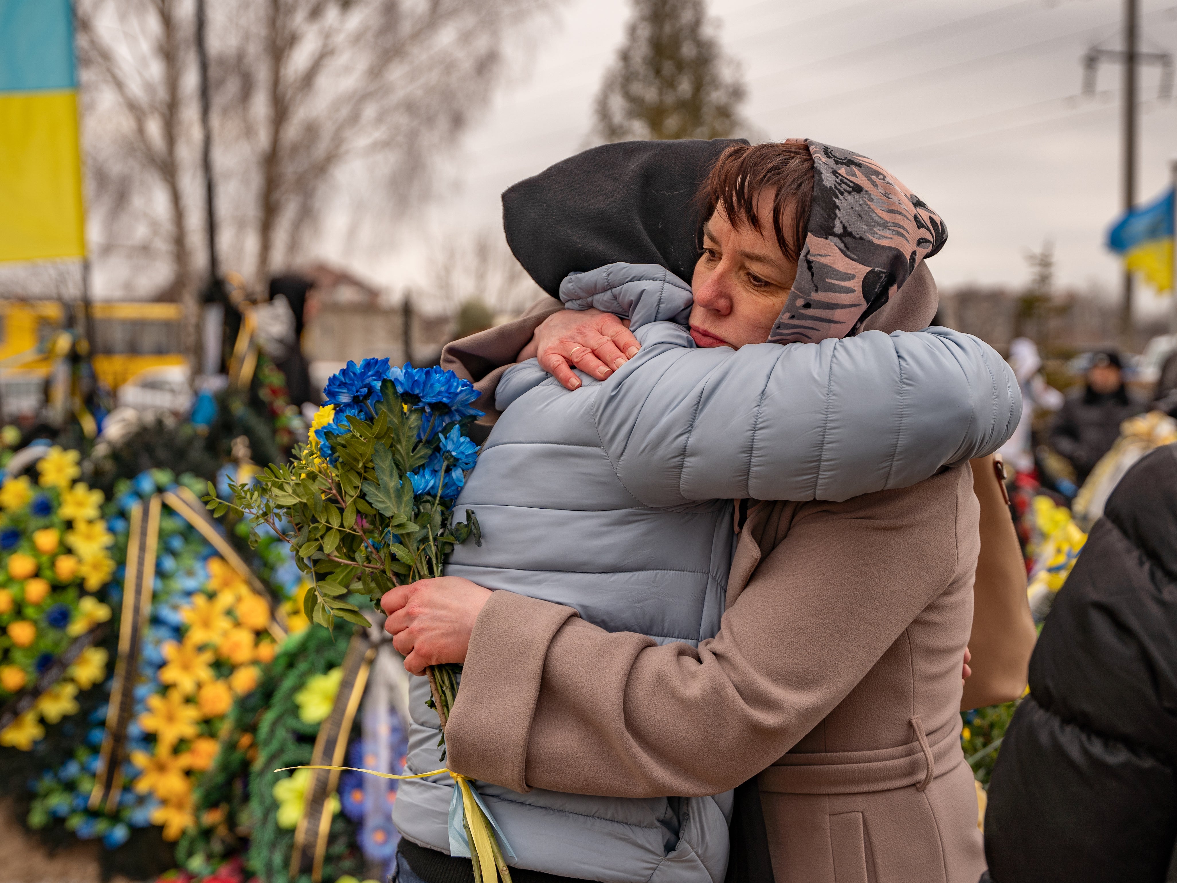Tetiana, whose son died fighting in Bakhmut a few weeks ago, is hugged and comforted by a friend as they mark the one year anniversary of Russia’蝉 invasion of Ukraine