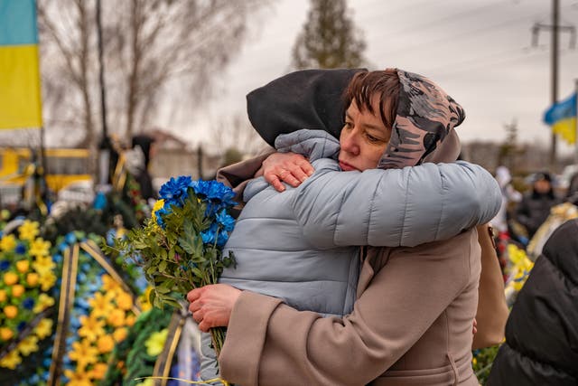 <p>Tetiana, whose son died fighting in Bakhmut a few weeks ago, is hugged and comforted by a friend as they mark the one year anniversary of Russia’s invasion of Ukraine</p>