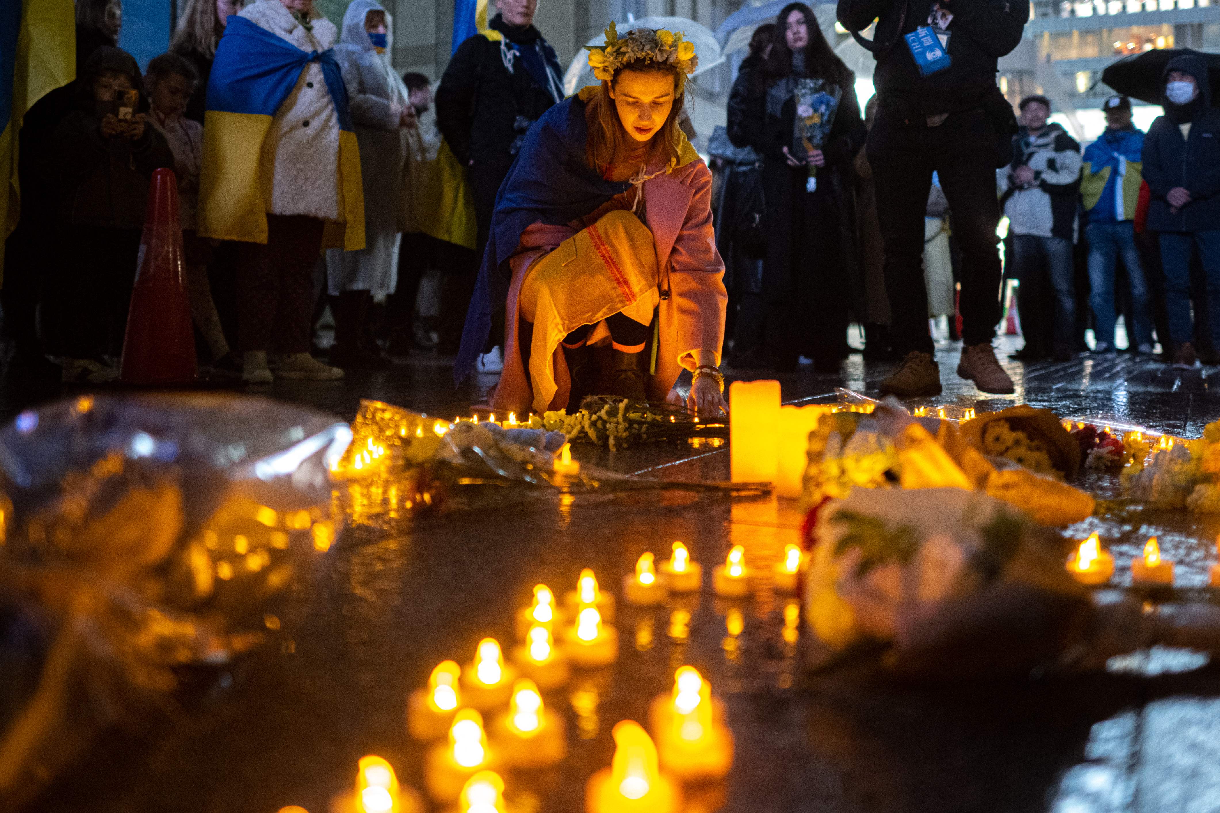 People take part in a candlelight vigil outside UN University to mark the one year anniversary of the Russian invasion of Ukraine, in Tokyo