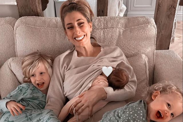 <p>Stacey Solomon breastfeeds baby Belle while her other two children, Rex and Rose, cuddle with her</p>