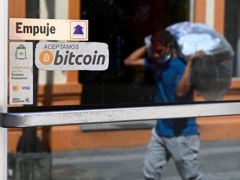 A man walks in front of a sign of a business where payments are accepted in bitcoin in San Salvador, on 17 November, 2022
