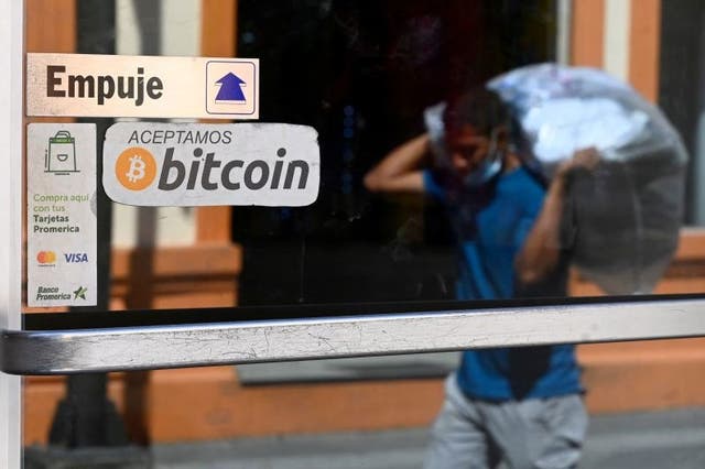 <p>A man walks in front of a sign of a business where payments are accepted in bitcoin in San Salvador, on 17 November, 2022</p>