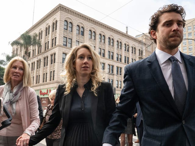 <p>Elizabeth Holmes (C), founder and former CEO of blood testing and life sciences company Theranos, walks with her mother Noel Holmes and partner Billy Evans into the federal courthouse for her sentencing hearing on November 18, 2022 in San Jose, California</p>