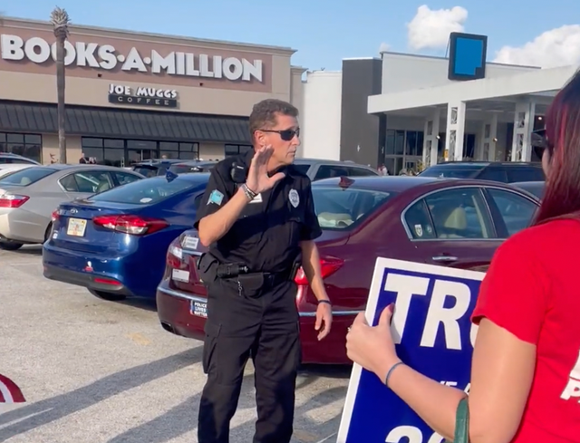 <p>A police officer speaking to Trump supporters outside the book signing event</p>