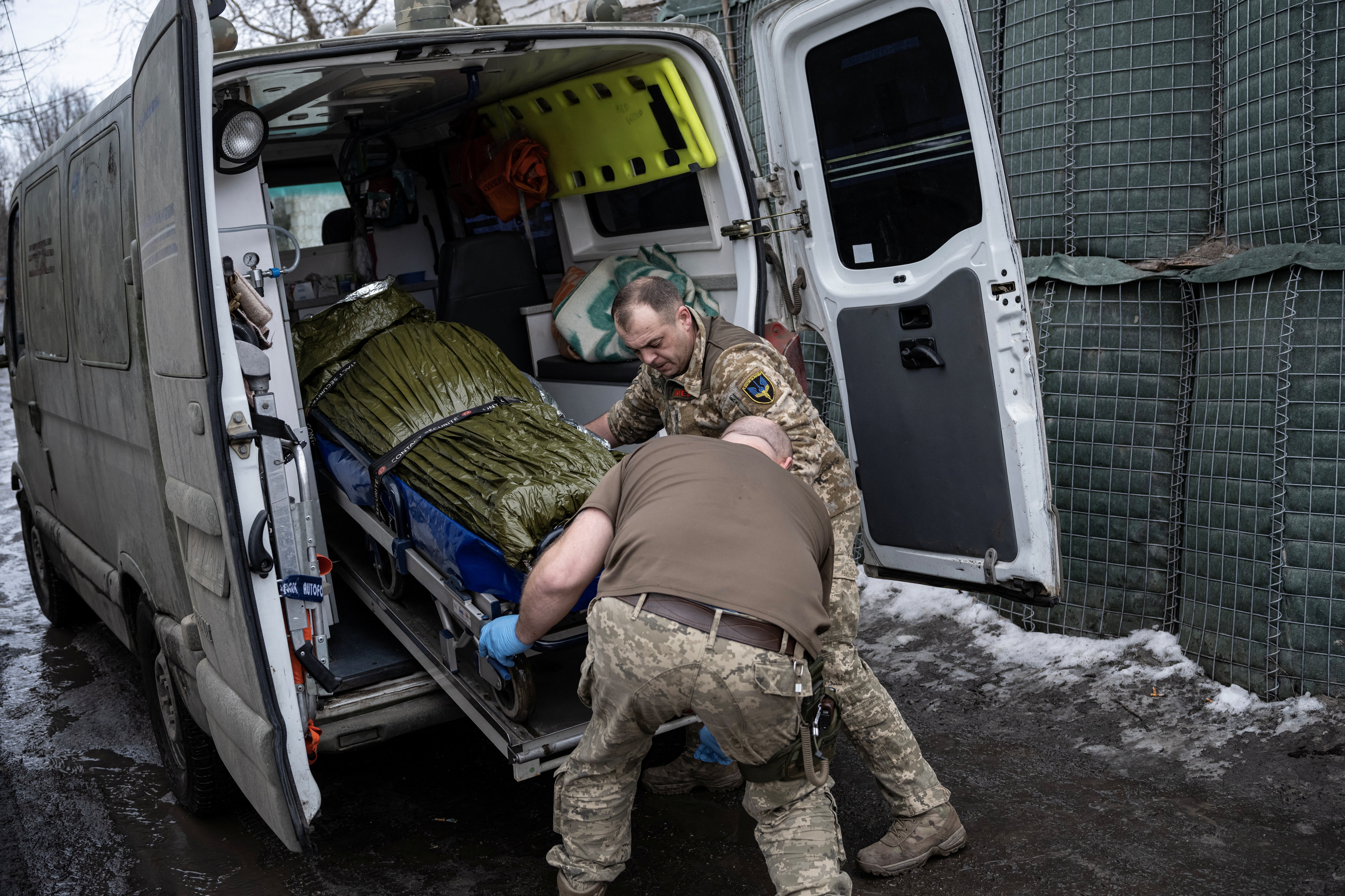 Medics place a wounded soldier in an emergency vehicle to transport him to a hospital