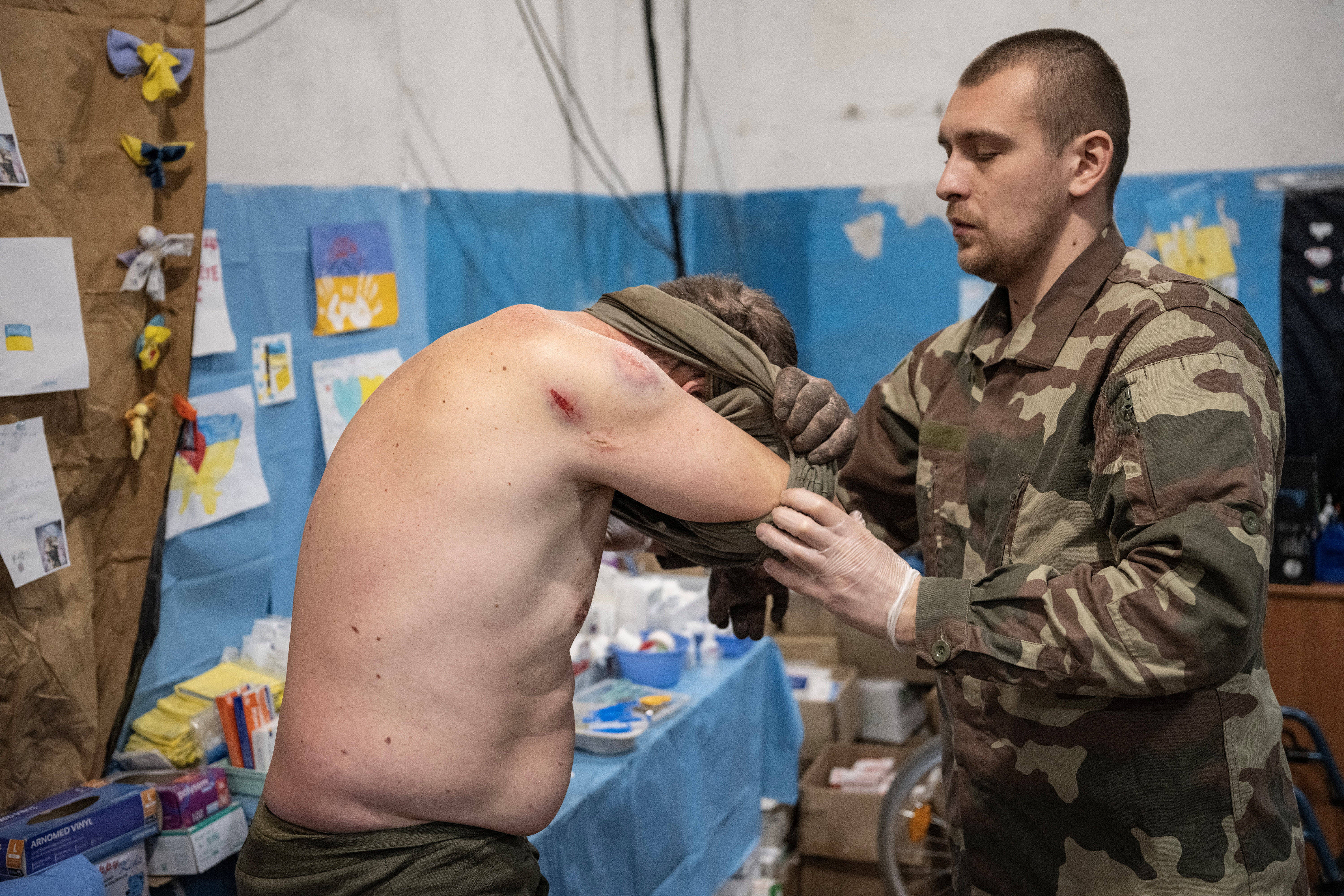 Volodymyr assists a wounded soldier