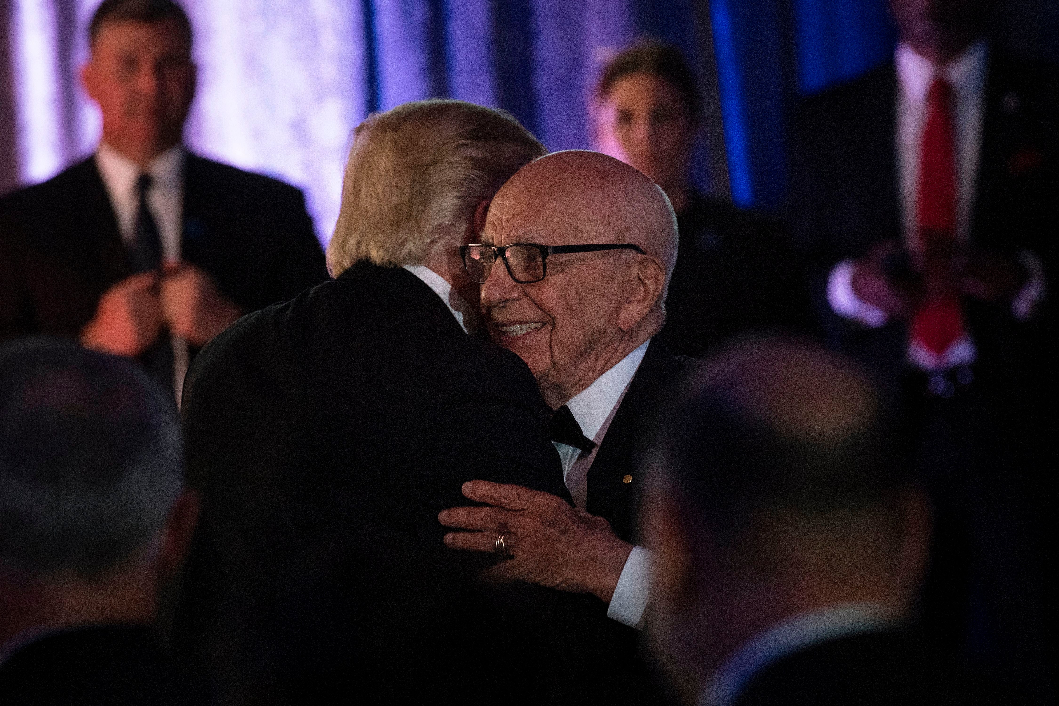 US President Donald Trump (L) is embraced by Rupert Murdoch, Executive Chairman of News Corp, during a dinner to commemorate the 75th anniversary of the Battle of the Coral Sea during WWII onboard the Intrepid Sea, Air and Space Museum May 4, 2017 in New York