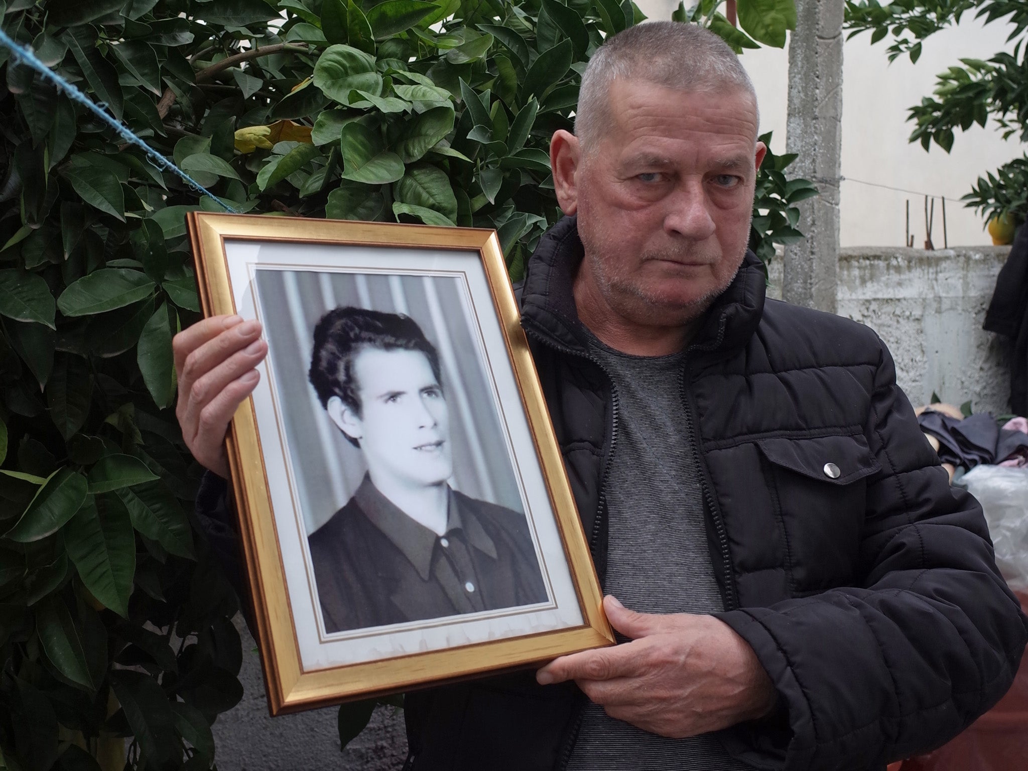 Zef Ndoj, holding a photo of his brother, whose body he found after more than 20 years