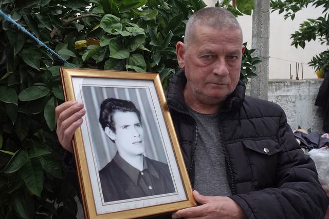 <p>Zef Ndoj, holding a photo of his brother, whose body he found after more than 20 years </p>