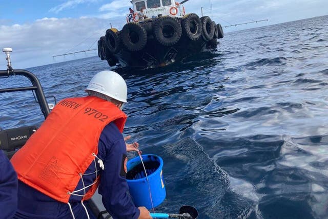 <p>A coast guard personnel collects water samples from an oil spill in the waters off Naujan, Oriental Mindoro</p>
