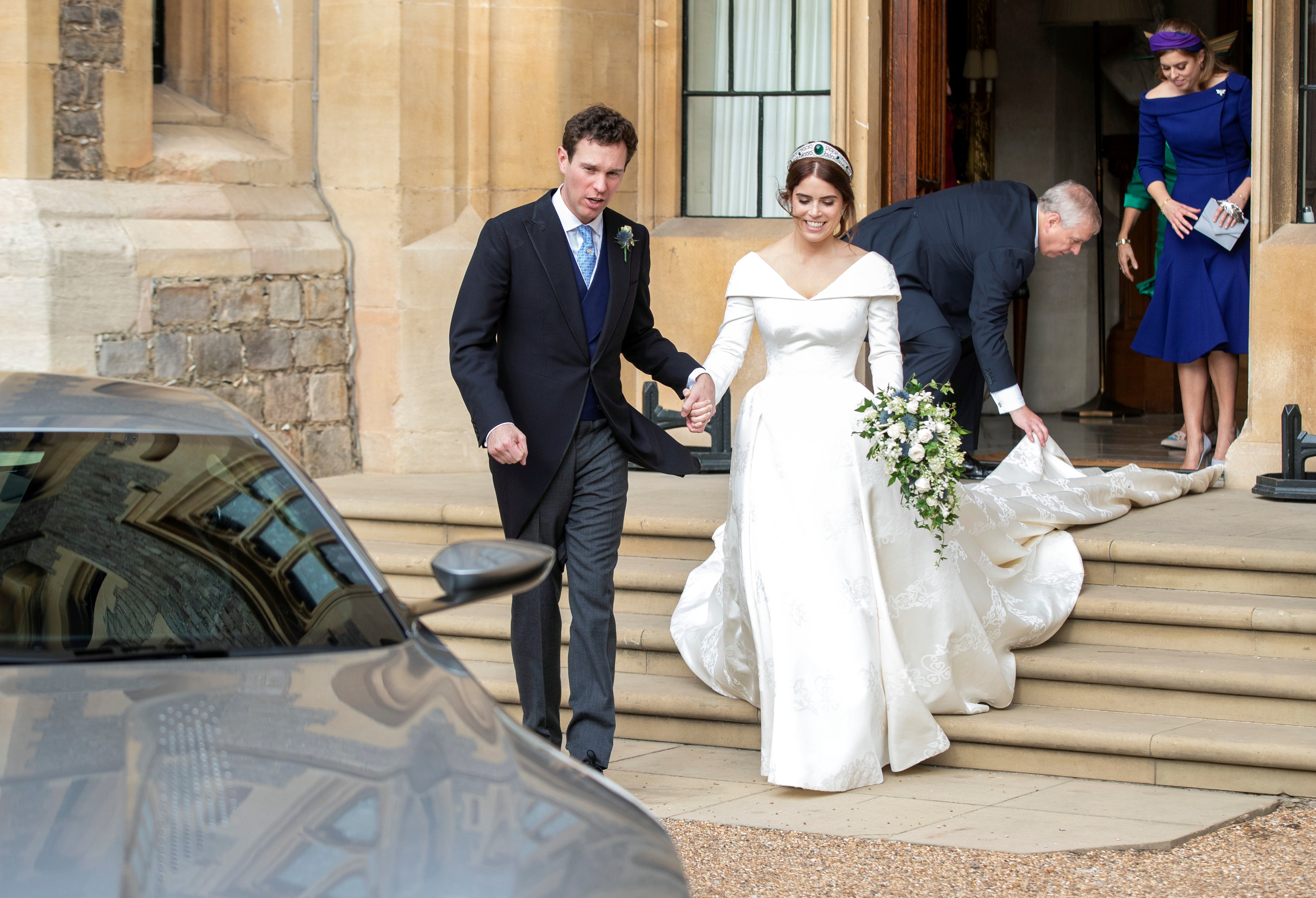 Princess Eugenie of York reacts as she and and her husband Jack Brooksbank walk to an Aston Martin DB10 as they leave Windsor Castle for Royal Lodge