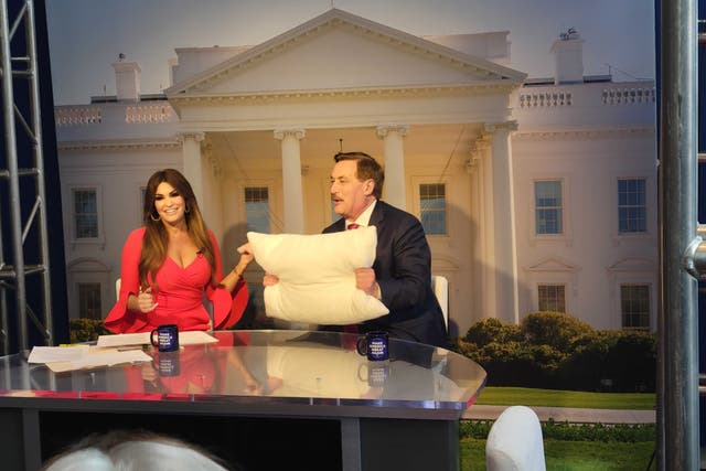 <p>Mike Lindell holds up a MyPillow product as he is interviewed by Kimberly Guilfoyle at CPAC</p>