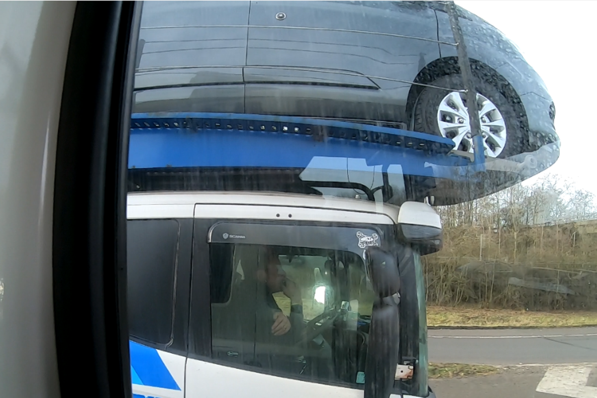 Driver caught using elbow to steer car transporter on busy motorway