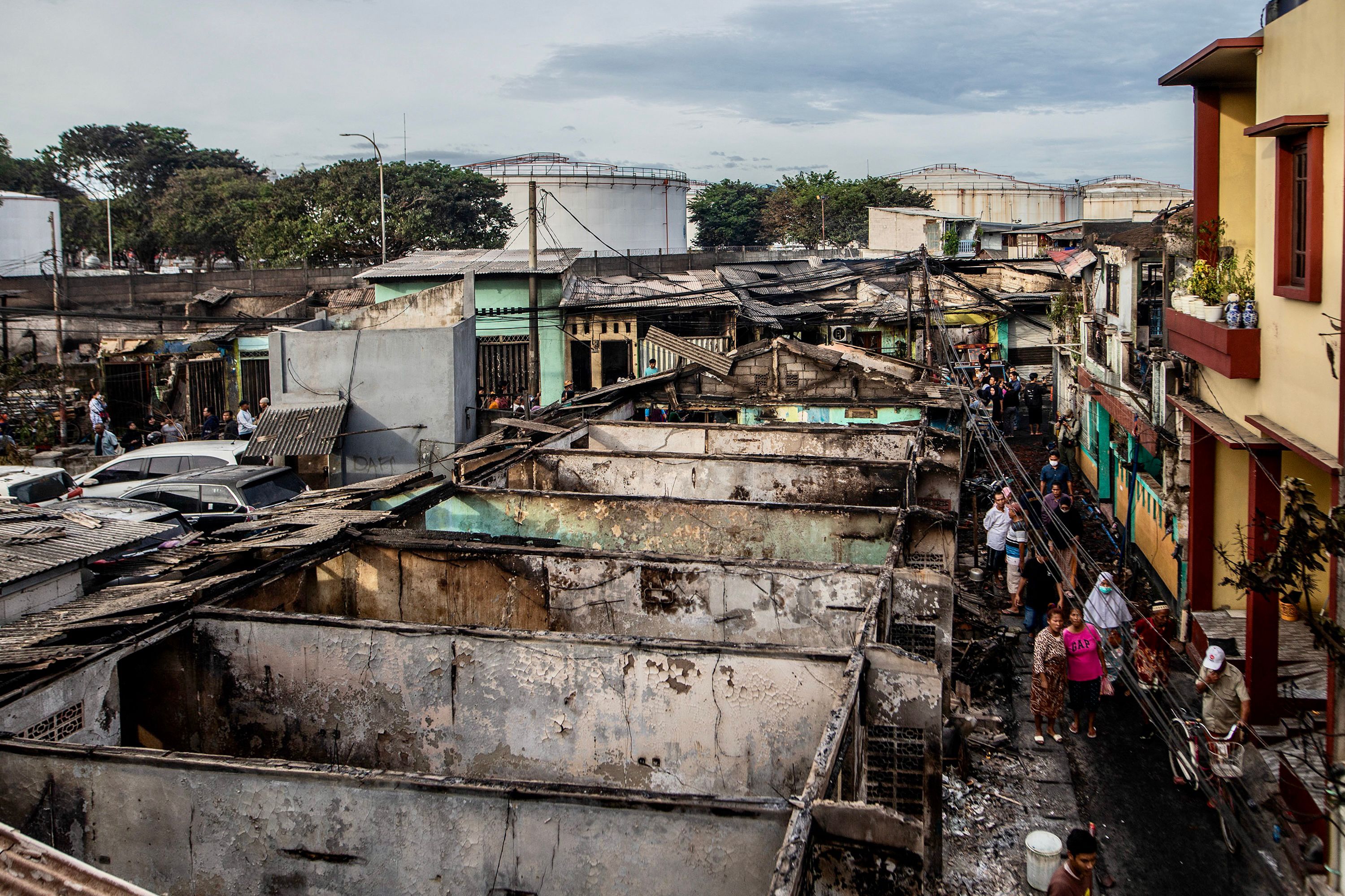 People look at burnt houses in a residential area in Plumpang, north Jakarta on 4 March 2023, after a fire at a nearby state-run fuel storage depot run by energy firm Pertamina