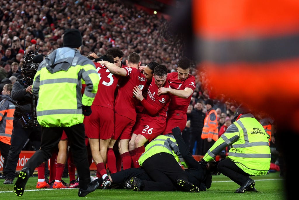 <p>A pitch invader is tackled by stewards after colliding with Liverpool player Andy Robertson</p>