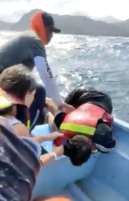 A tourist is pulled into a rescue boat after a vessel was capsized near the coast of Columbia