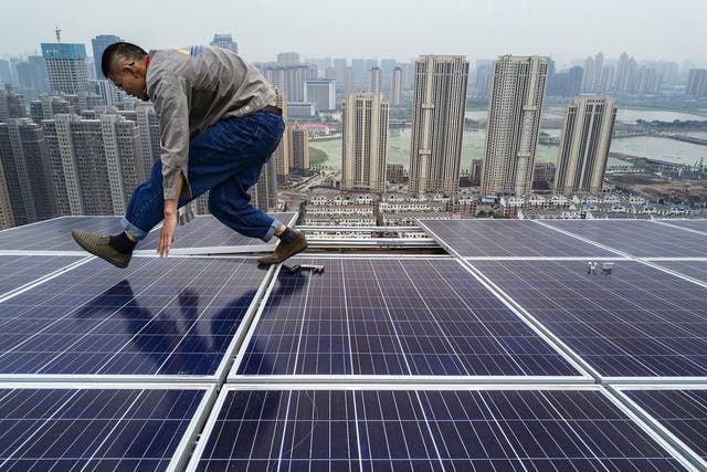 <p>A Chinese worker installing solar panels on the roof of a 47 story building in Wuhan, China, on 15 May, 2017</p>