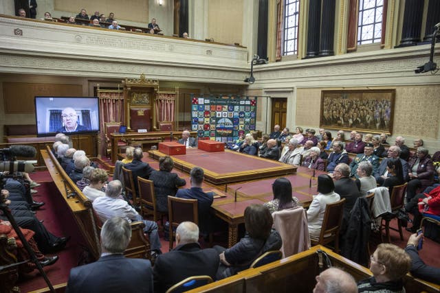 Attendees of a Victims’ Day event in the Senate Chamber of the Northern Ireland Assembly watch a pre-recorded message from Paul Wilson, son of Irish nationalist politician and member of the Senate of Northern Ireland Paddy Wilson, who was killed by the loyalist Ulster Freedom Fighters in 1973 (Liam McBurney/PA)