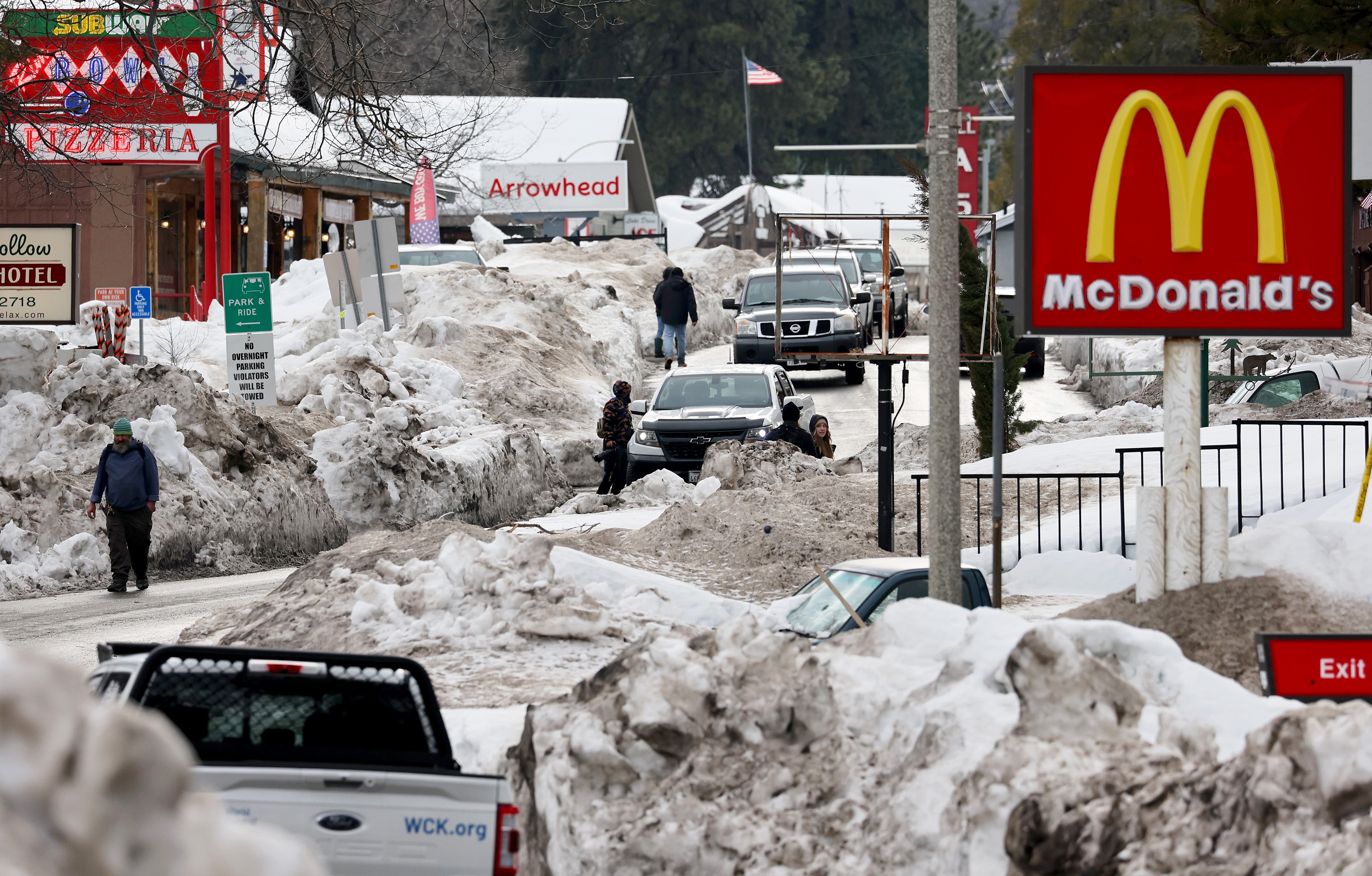 <p>People walk along a plowed street after a series of winter storms dropped more than 100 inches of snow in the San Bernardino Mountains in Southern California on March 6, 2023 in Crestline, California</p>