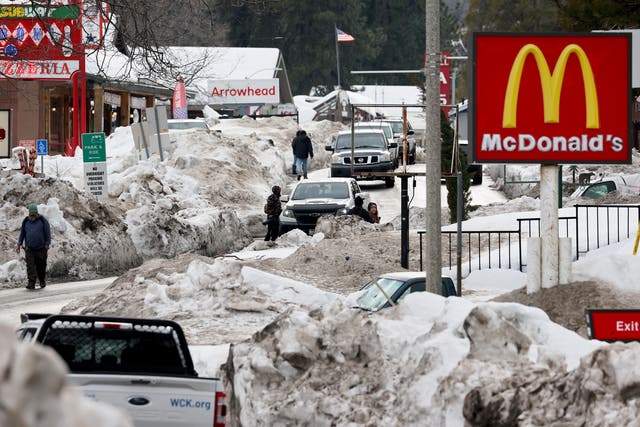 <p>People walk along a plowed street after a series of winter storms dropped more than 100 inches of snow in the San Bernardino Mountains in Southern California on March 6, 2023 in Crestline, California</p>