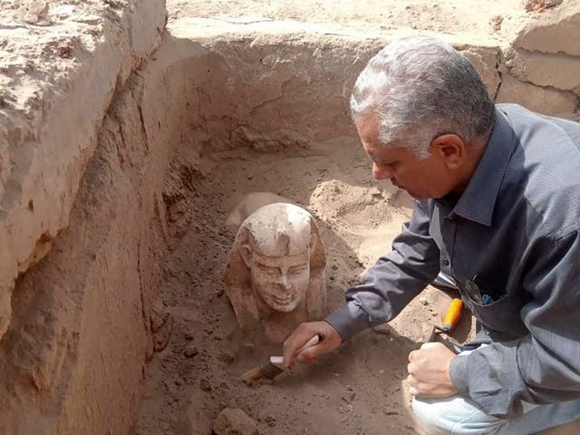<p>An undated handout photo made available by the Egyptian Ministry of Antiquities on 6 March 2023 shows an archeological worker unearthing a Sphynx statue during excavation work at the eastern side of Dendara Temple in Qena governorate, Egypt</p>
