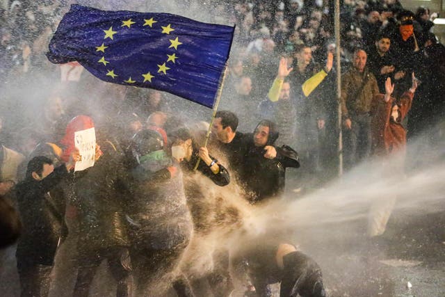 <p>A woman brandishing a European Union flag is sprayed by a water cannon near the Georgian parliament in Tbilisi</p>
