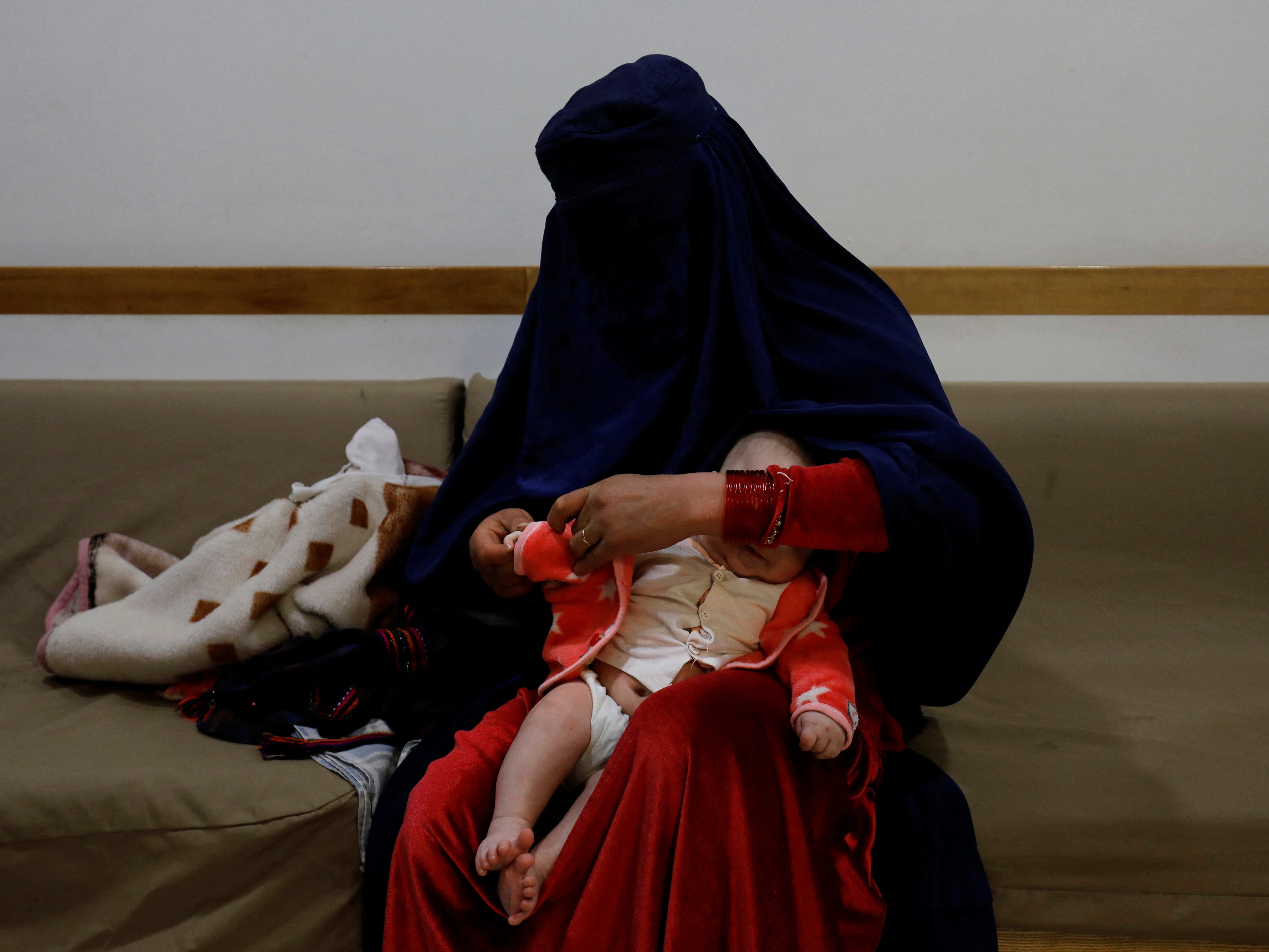 A woman dresses up her child at a hospital in Bamiyan