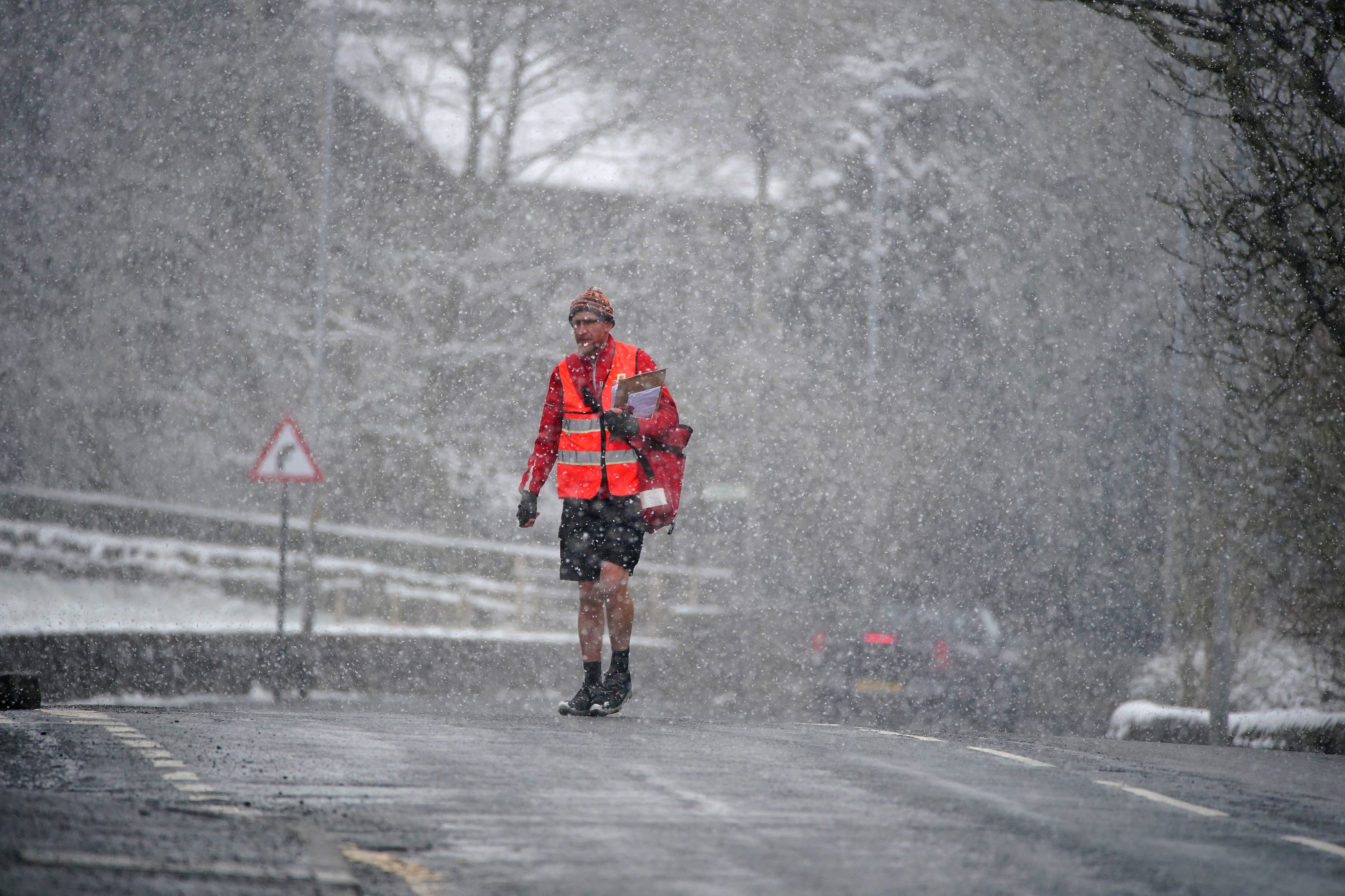A postie battles heavy snow on his delivery rounds in Oldham, Greater Manchester on Thursday