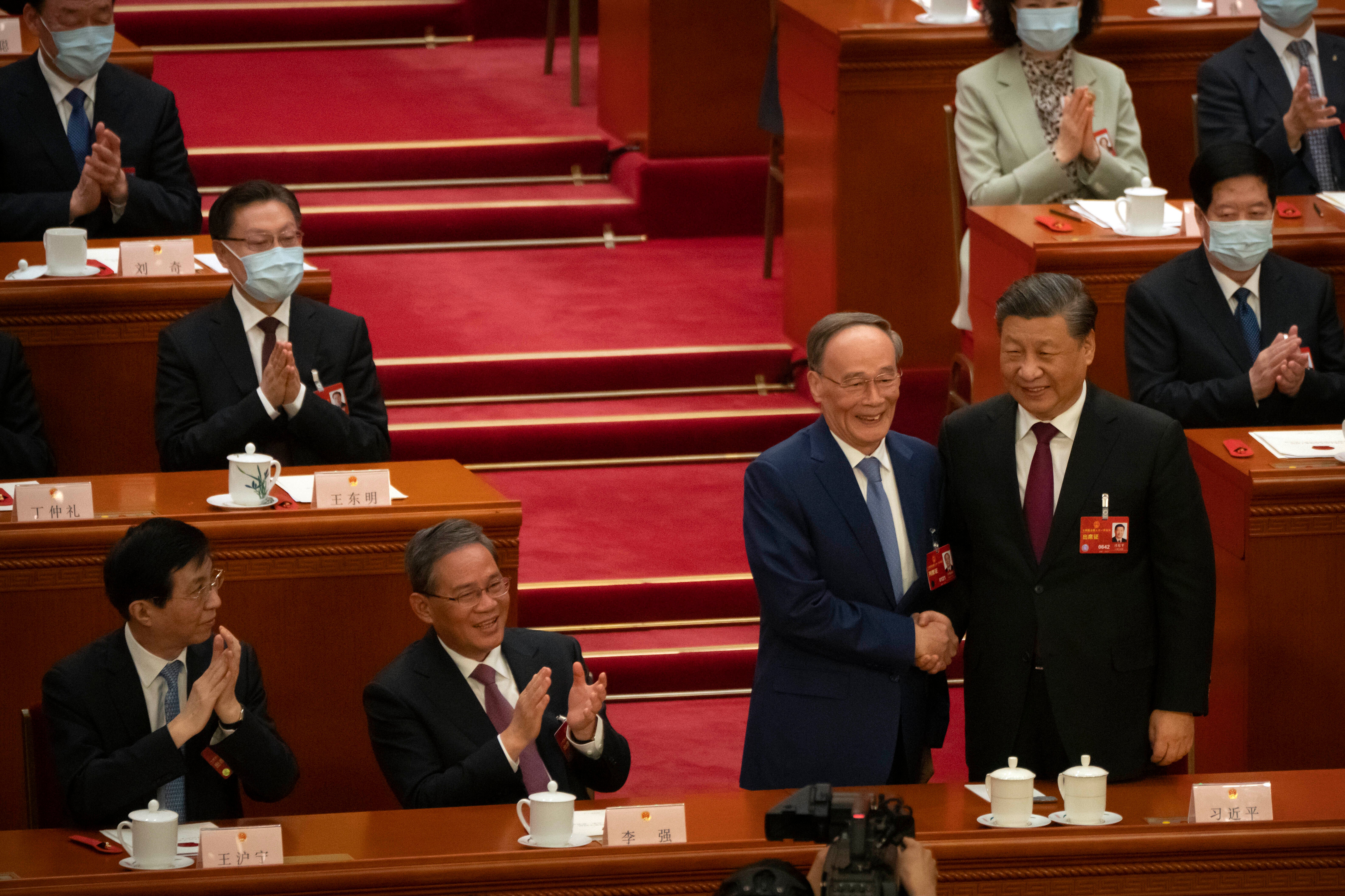 Chinese president Xi Jinping, right, shakes hands with Wang Qishan during a session of China's National People's Congress