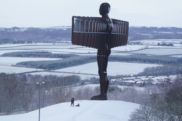 People sledging in the snow at the foot of Antony Gormley’s Angel of the North sculpture in Gateshead, Tyne and Wear (Owen Humphreys/PA)