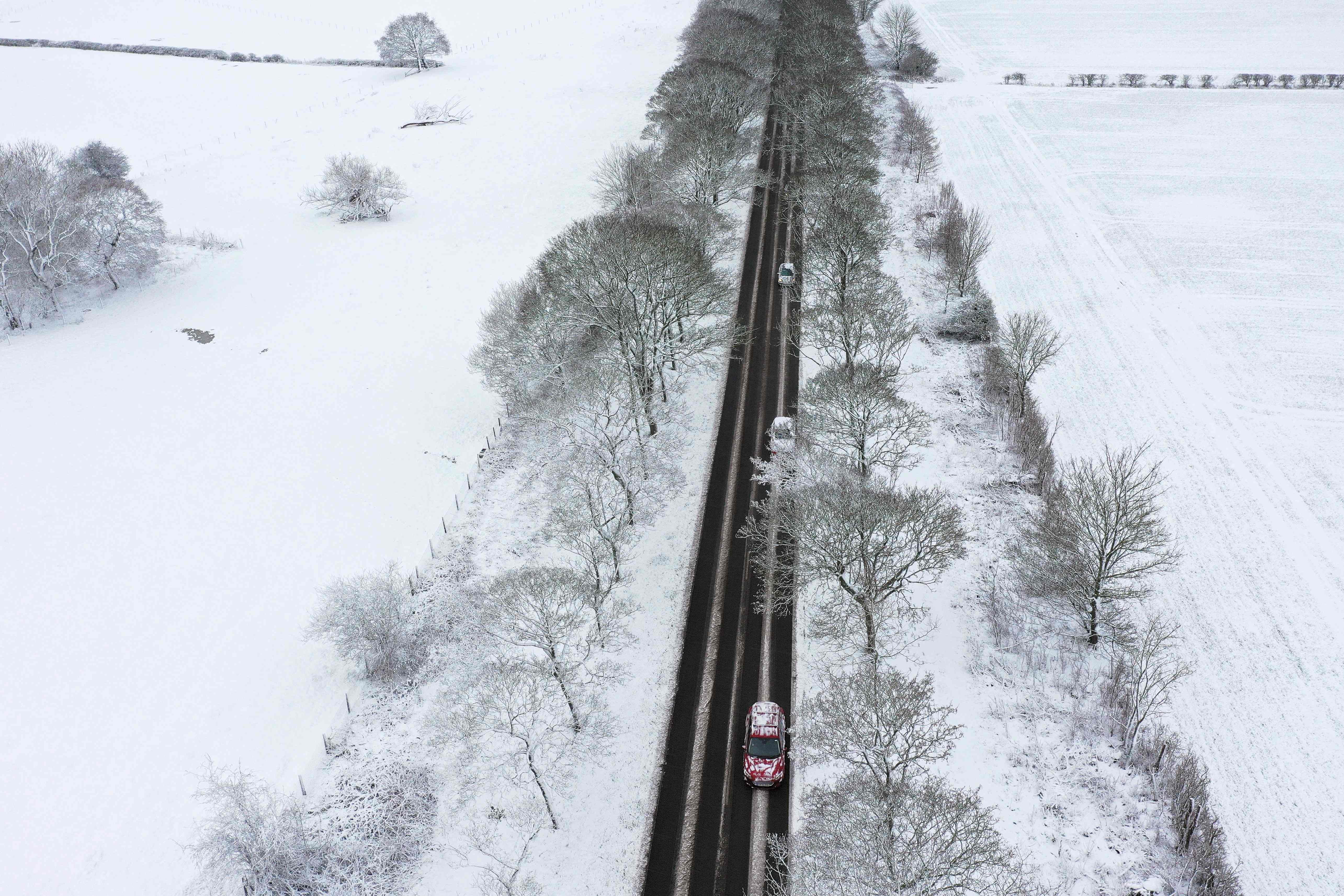 Cars are driven along a snow-covered road in Lever Causeway, near Birkenhead