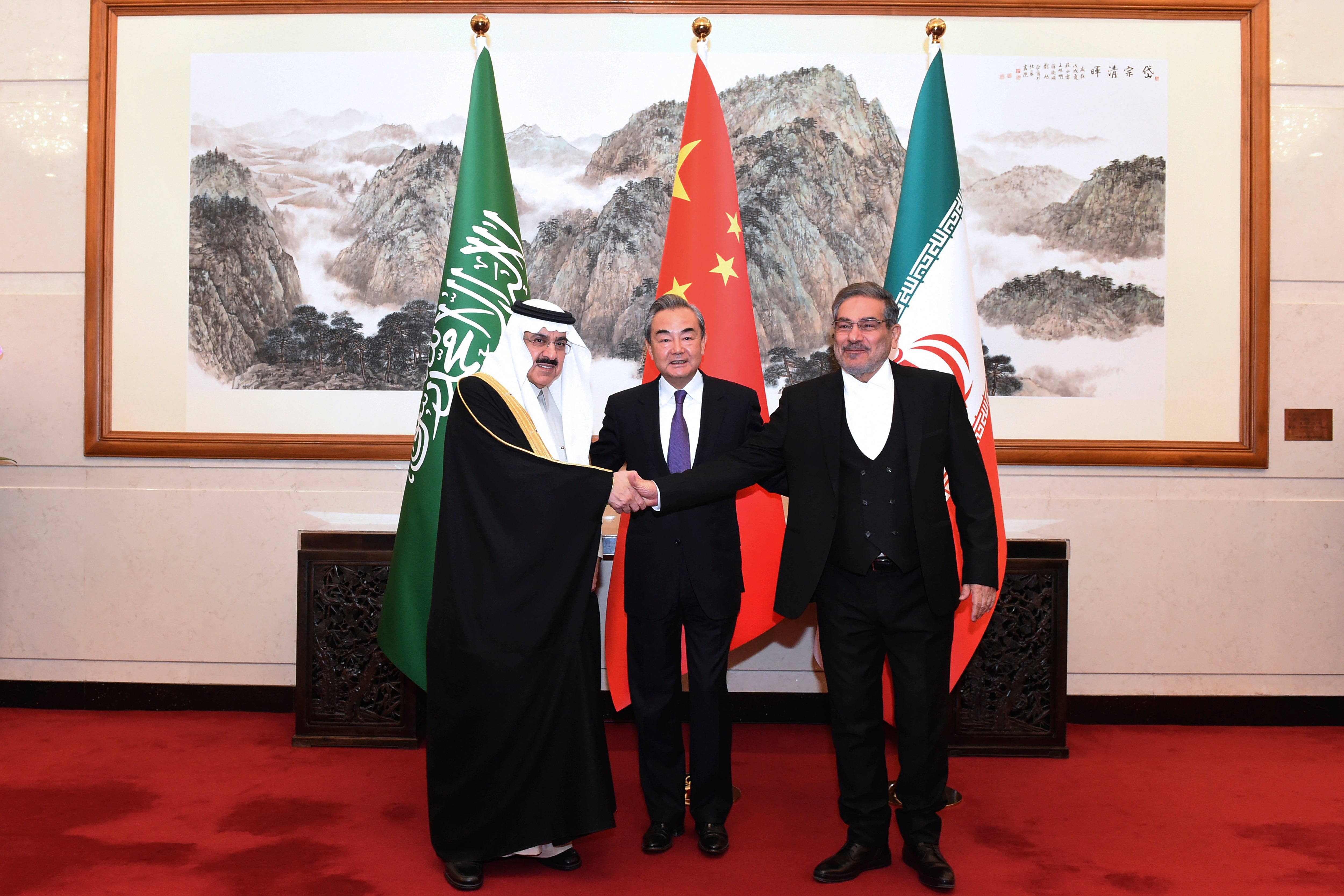 Ali Shamkhani, the secretary of Iran's Supreme National Security Council, right, shakes hands with Saudi national security adviser Musaad bin Mohammed al-Aiban, left, as Wang Yi, China's most senior diplomat, looks on