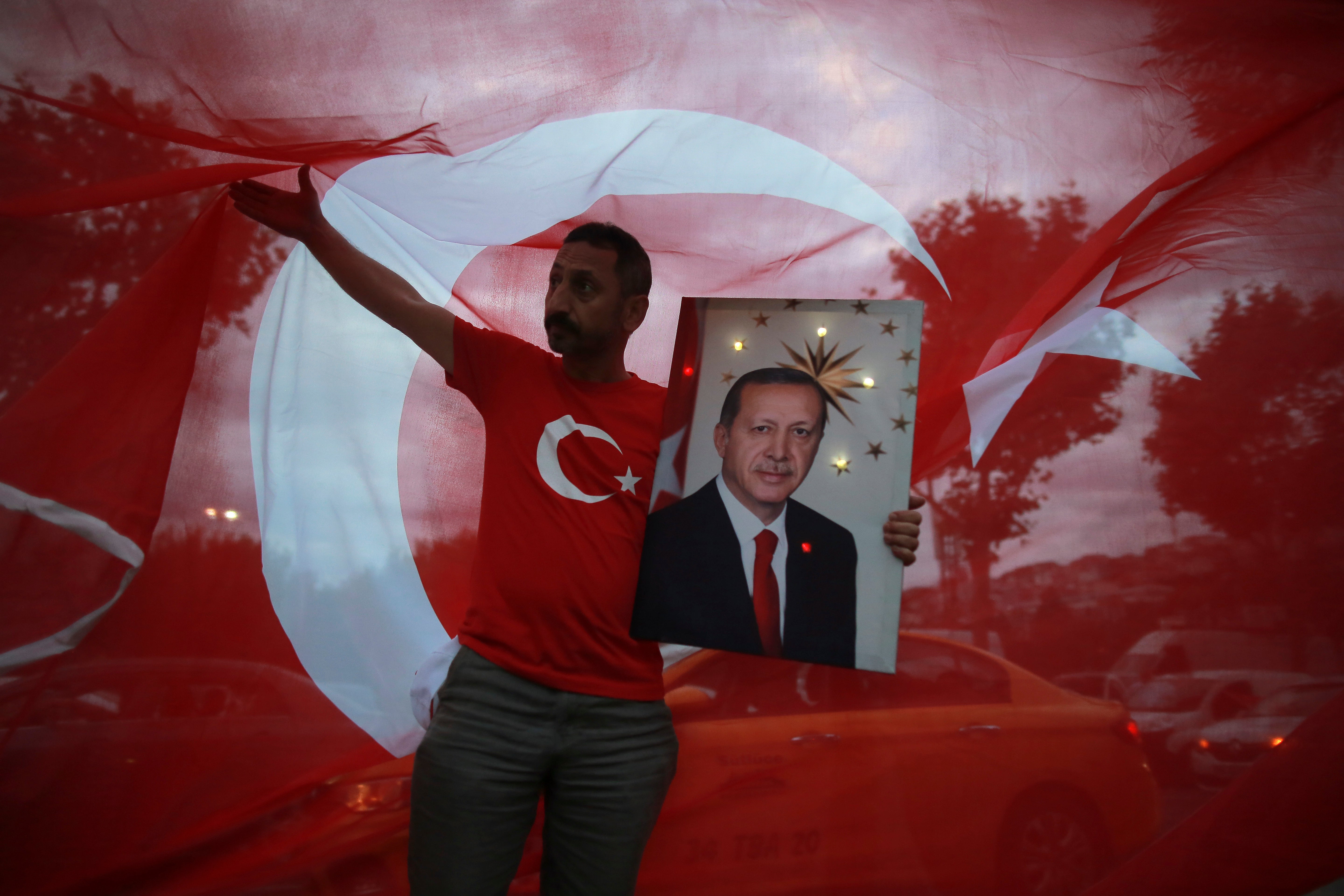 A man holds a picture of Turkey's President and ruling Justice and Development Party, or AKP, leader Recep Tayyip Erdogan