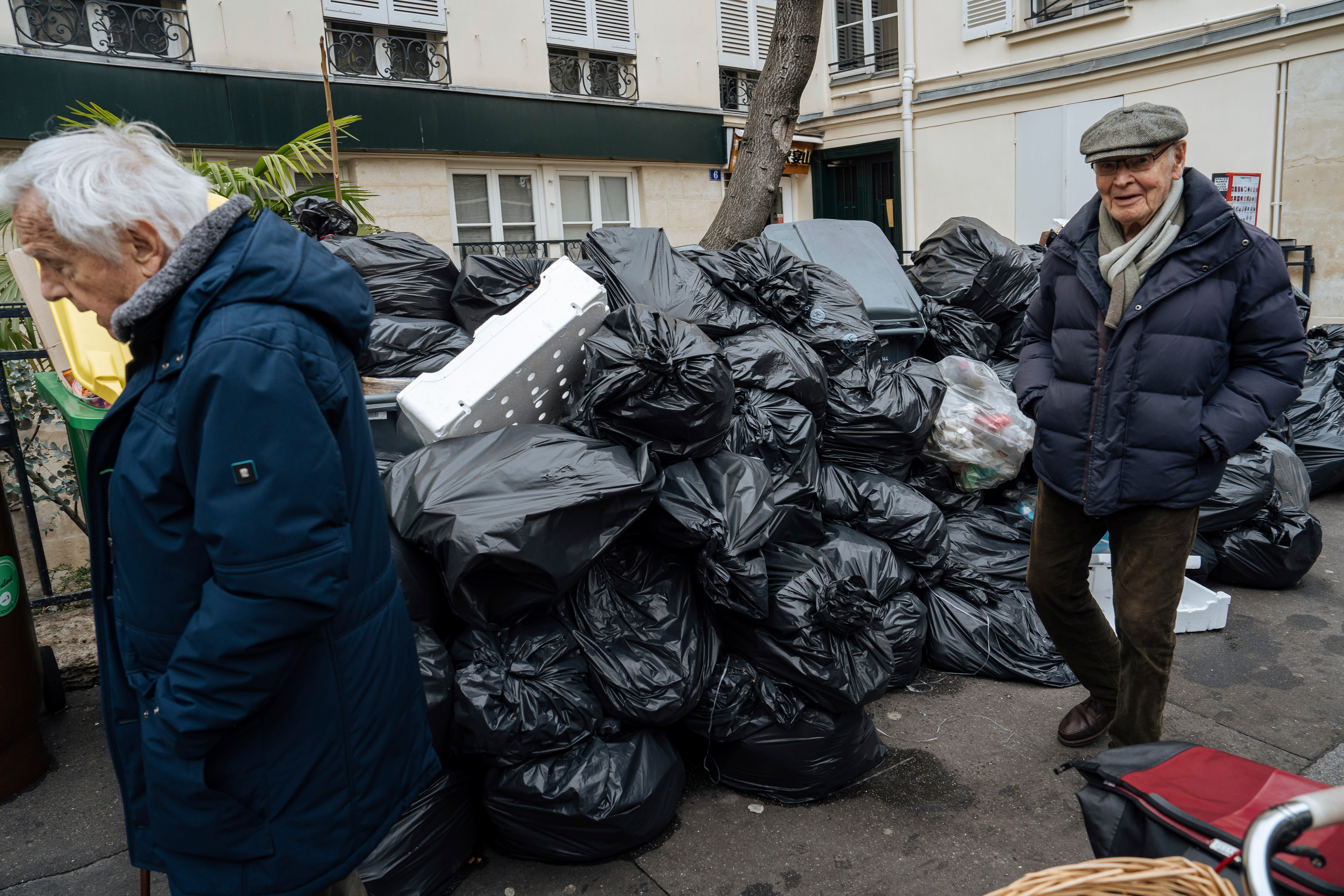 People walk past piles of bin bags in Paris