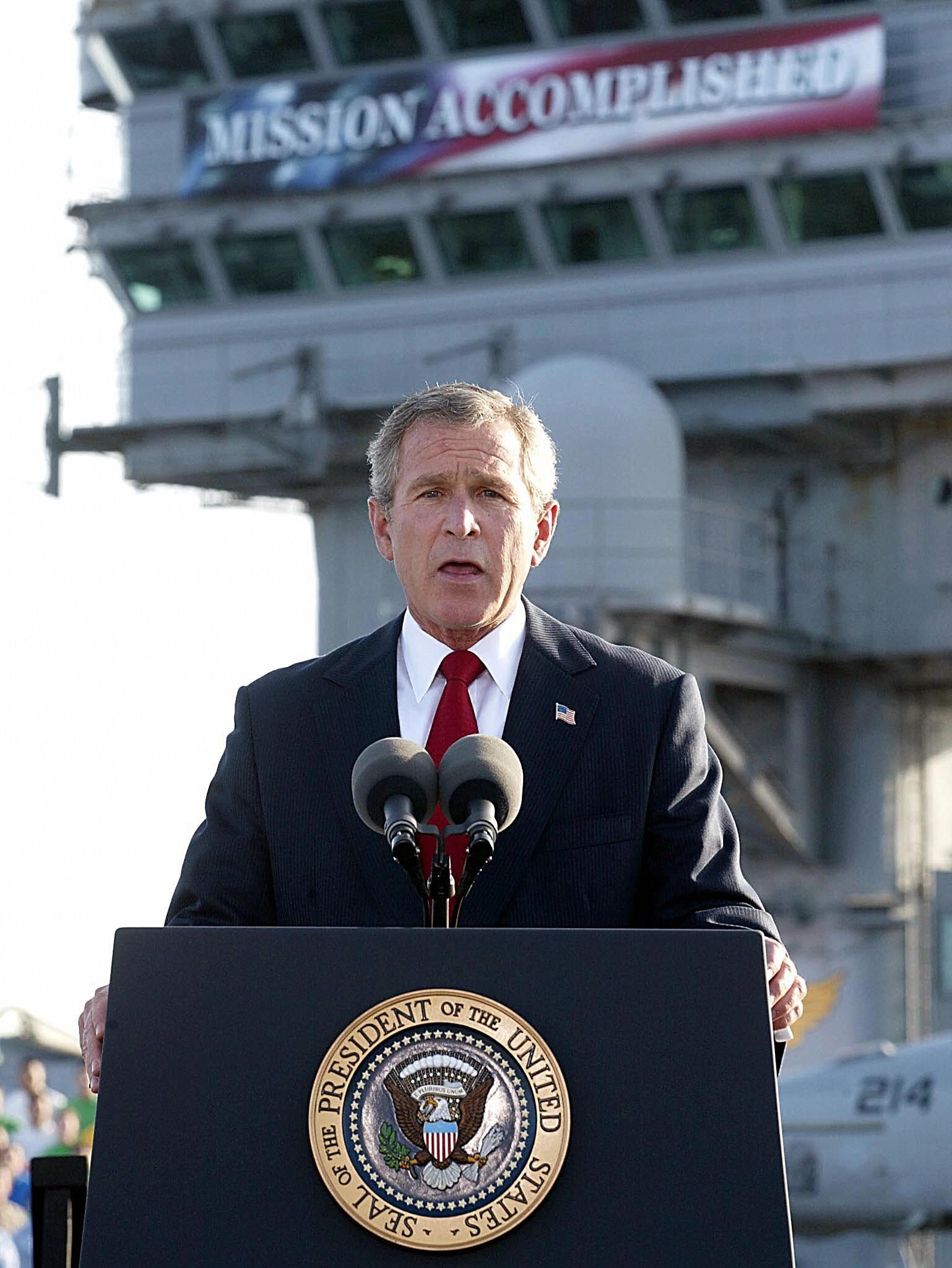 George W Bush aboard aircraft carrier USS Abraham Lincoln in front of a ‘Mission Accomplished’ banner