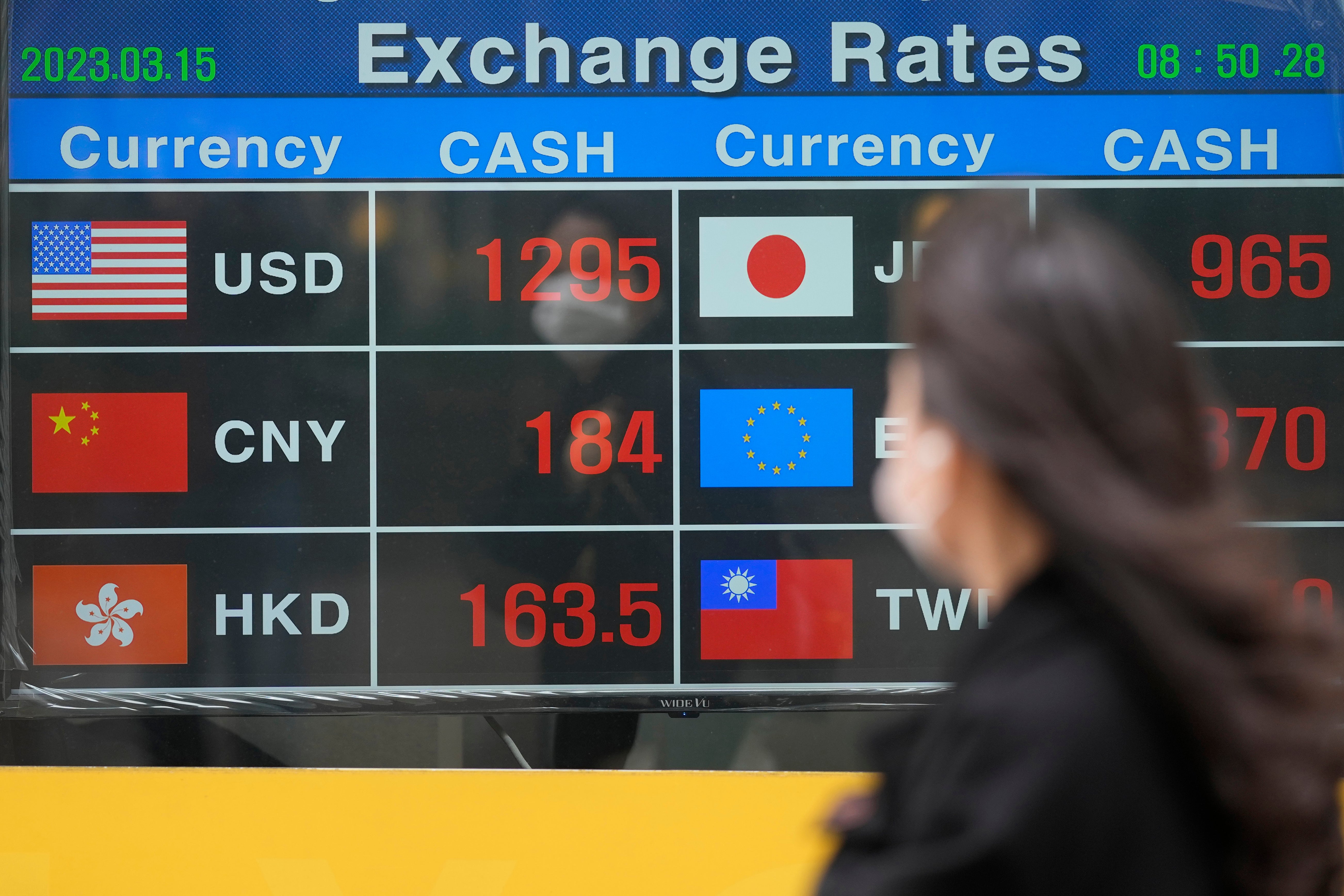 FILE-A woman wearing a face mask looks at an electronic foreign currency exchange rates in downtown Seoul, South Korea