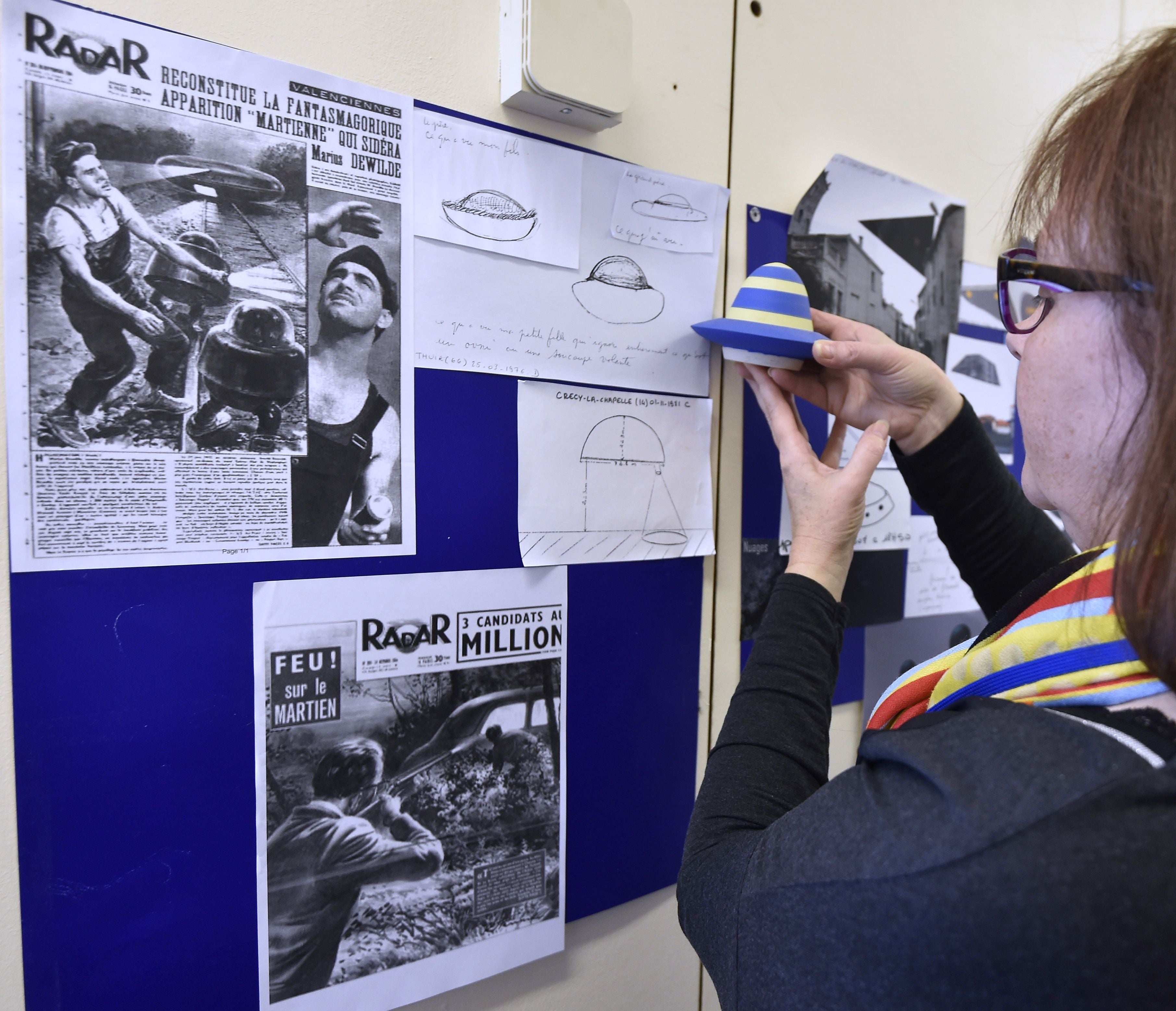 <p>A woman looks at an illustration of an Ununidentified flying object (UFO) on December 17, 2015, in the GEIPAN unit of the French Space Agency CNES </p>