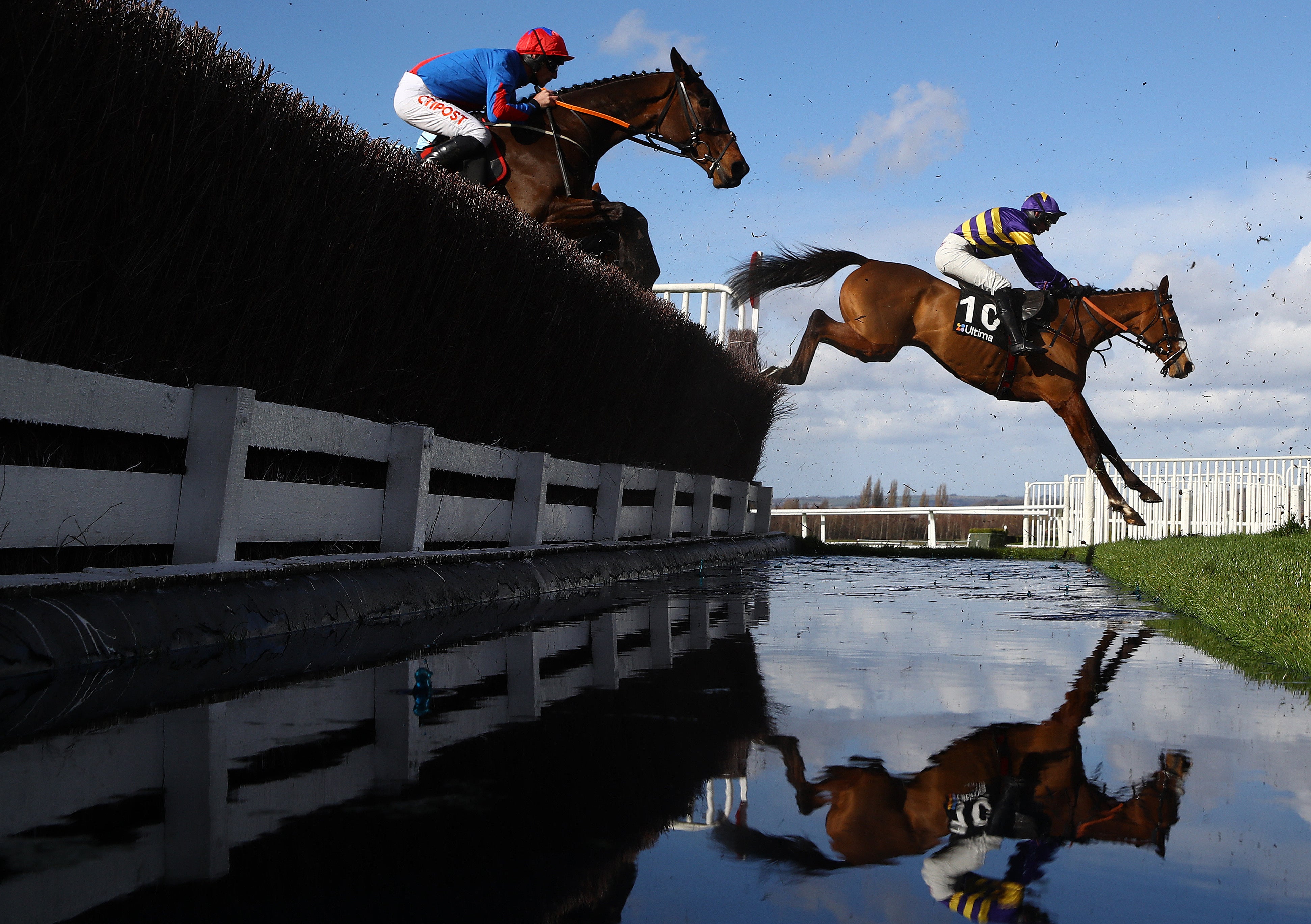 Derek Fox (r) riding Corach Rambler takes the water jump on his way to winning the Ultima Handicap Chase