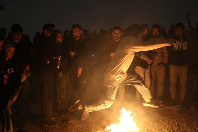 <p>A woman leaps over fire during the traditional ‘Red Wednesday’ festival in a park in Tehran</p>