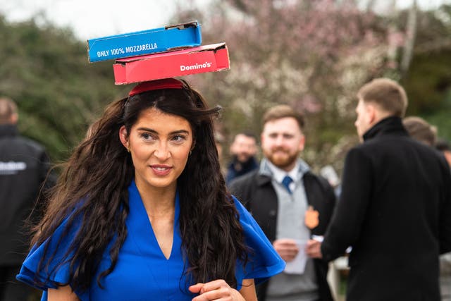 <p>A woman wearing a Domino’s Pizza fascinator at Cheltenham Festival on 15 March 2023</p>