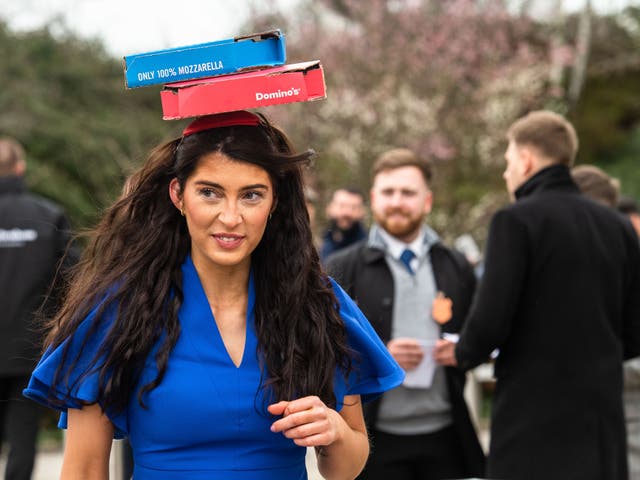 <p>A woman wearing a Domino’s Pizza fascinator at Cheltenham Festival on 15 March 2023</p>